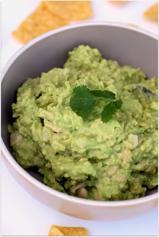 White bean avocado guacamole dip with tomatoes, red onions, garlic, lime juice, cilantro and jalapeno.