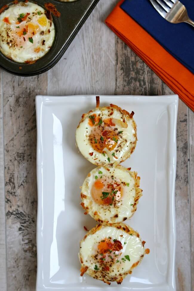 Baked Egg Muffins with Hash Brown Crust: cheesy hash brown nests filled with a perfectly cooked baked egg and topped with a drop of hot sauce and crispy bacon crumbles. A perfect eat-on-the-go breakfast. 