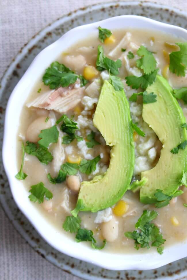 Slow Cooker Healthy White Turkey Chili--a creamy dried white bean chili with tender bites of turkey, creamy broth made with protein-packed Greek yogurt, crumbly queso fresco, slices of avocado and a splash of lime juice for flavor. 