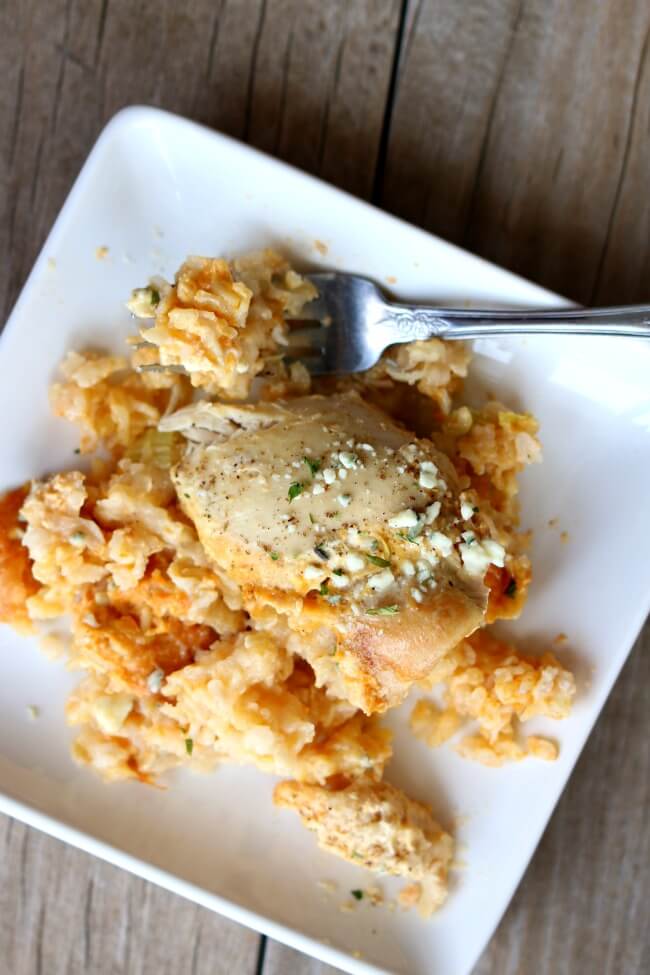 Slow Cooker Buffalo Chicken Rice Casserole--this crockpot casserole has all your favorite flavors from a platter of chicken wings in one pan. It starts with brown rice (you can substitute white if you'd like), sliced celery, chicken, spicy buffalo sauce and then it's topped with bleu cheese.