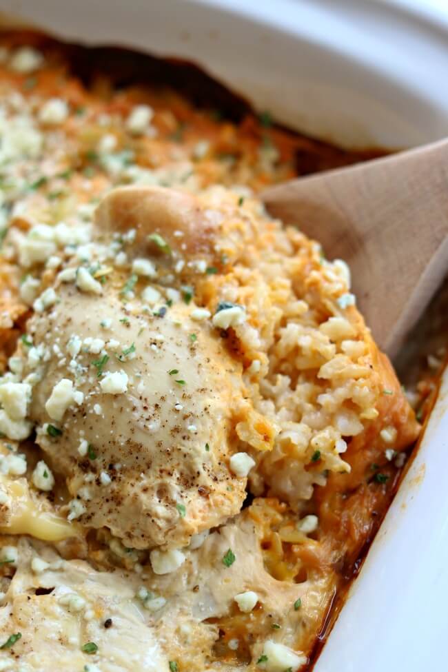 Slow Cooker Buffalo Chicken Rice Casserole--this crockpot casserole has all your favorite flavors from a platter of chicken wings in one pan. It starts with brown rice (you can substitute white if you'd like), sliced celery, chicken, spicy buffalo sauce and then it's topped with bleu cheese.