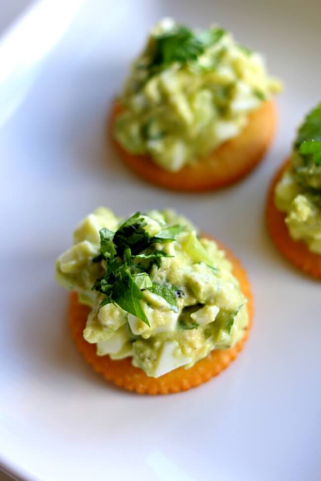 Avocado Egg Salad RITZ Cracker Snacks—smashed avocado is mixed with hard boiled eggs, chopped tomatillos, creamy Greek yogurt and cilantro and then slathered on top of a RITZ Cracker for a perfect snack or appetizer. 