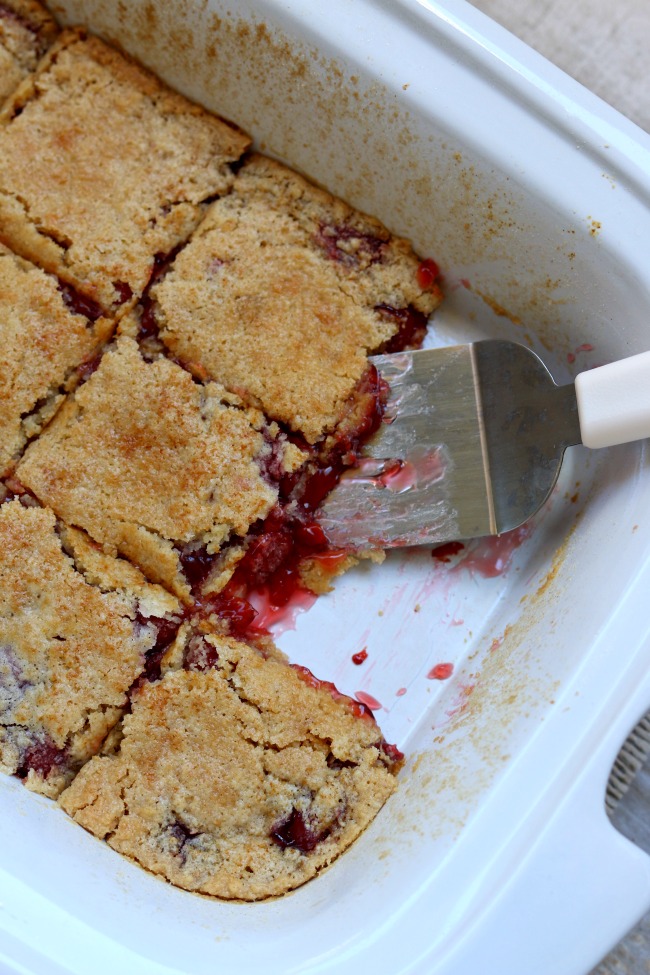 Slow Cooker 3 Ingredient Cherry Dump Cake--all you need to make this recipe is a cake mix, cherry pie filling and butter. Dump all the ingredients in your slow cooker and turn it on. This recipe is so easy and hands off but tastes amazing especially when served with vanilla ice cream.
