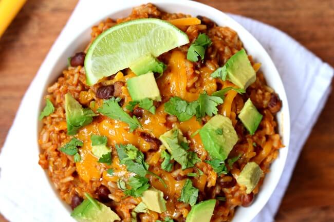 Instant Pot Cheesy Enchilada Rice--brown rice is pressure cooked with enchilada sauce and spices in minutes and then topped with sharp cheddar, diced avocado and a wedge of lime. 