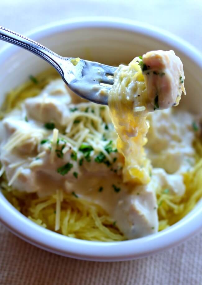 Instant Pot Chicken Alfredo Spaghetti Squash--chicken cooks in your instant pot at the same time as your spaghetti squash and then a luscious sauce is stirred together with the chicken and served over the top of the spaghetti squash 