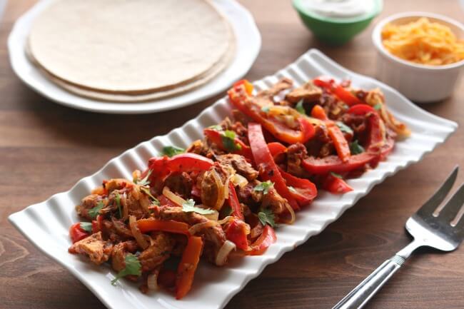 Instant Pot/Slow Cooker Pork Chop Fajitas--make amazingly flavorful fajitas (thanks to a secret ingredient) in the Instant Pot or slow cooker with pork chops. When you buy those inexpensive mega packs of pork chops use this recipe to mix up dinner and bring something new to the table (literally).