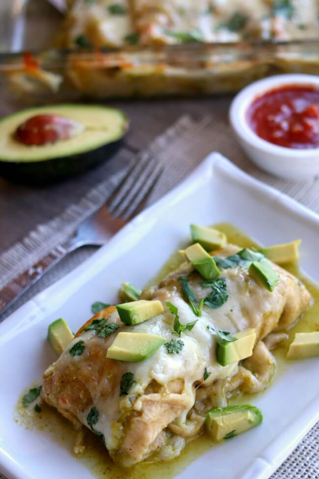 Instant Pot Smothered Green Sauce Enchiladas--homemade Cafe Rio style mild tomatillo sauce is simmered in your electric pressure cooker along with chicken breasts to create the base of your enchiladas. The meal is finished off in the oven when shredded chicken, green sauce and monterey jack cheese are wrapped in flour or corn tortillas and baked. Top each enchilada with avocado slices and a bit of sour cream and you have a party in your mouth.