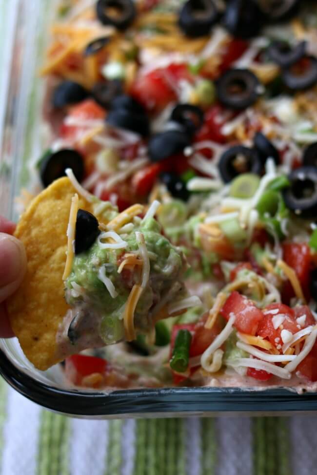 7 Layer Dip--this is the best 7 layer dip I have ever eaten! It starts with a layer of perfectly seasoned homemade refried beans (which you can make in the Instant Pot or slow cooker), then a layer of sour cream mixed with taco seasoning and salsa, next a layer of smashed avocados seasoned with lime juice and finally it's topped with diced tomatoes, green onions, cheese and olives. Every layer comes together in perfect harmony on top of a tortilla chip and popped into your mouth. 