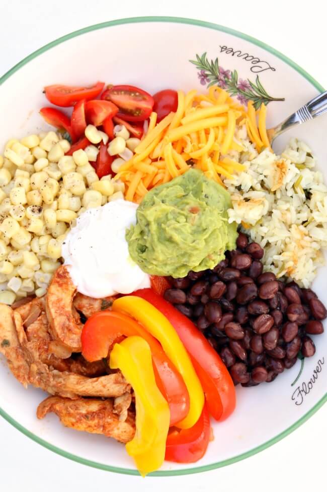 Instant Pot Chicken Fajita Bowls--the pot-in-pot cooking method allows you to cook cilantro lime rice, seasoned chicken, onions and bell peppers all together and in just a few minutes in your electric pressure cooker. Then they are layered in a bowl with cheese, sweet corn, tomatoes, black beans, sour cream and guacamole. It's definitely a fiesta in your mouth.