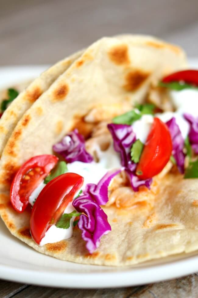 Alaska Cod Fish Tacos with Garlic Lime Sour Cream (slow cooker, instant pot or oven)--well seasoned flaky white fish is served wrapped up in a freshly cooked tortilla and topped with purple cabbage, tomatoes and the best sour cream of your life. A fresh, healthy and easy family friendly recipe that is perfect for any day of the week! Plus you can choose how you want to prepare it--oven, slow cooker or instant pot!