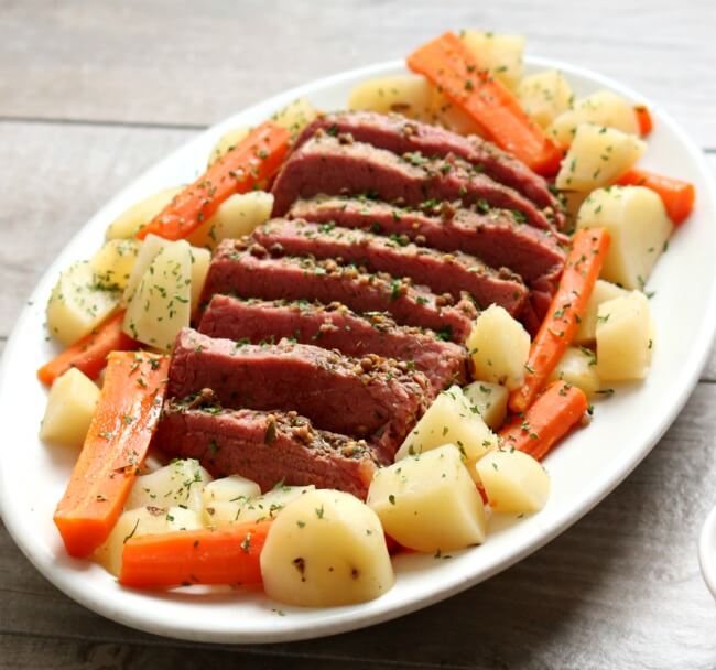 Slow Cooker Corned Beef Dinner with Mustard Sauce--a super easy (and delicious) method for making corned beef! Tender corned beef is sliced and served alongside carrots and potatoes (and if you want, cabbage). Top your corned beef with a tangy sauce made of sour cream, dijon mustard and garlic. A perfect dinner for St Patrick's Day (or any other day). 