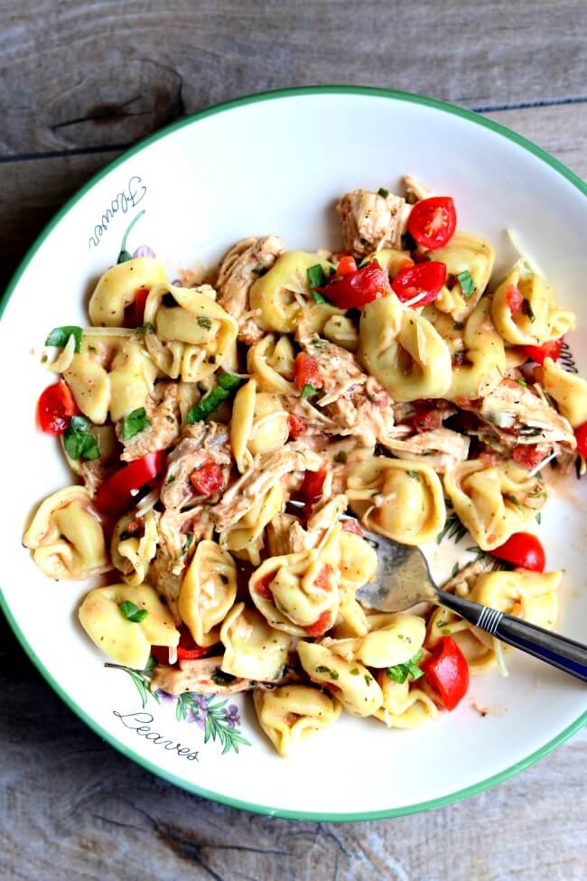 Slow Cooker Creamy Basil Chicken and Tortellini--tender bites of chicken breast and cheesy tortellini are served in a creamy tomato basil sauce. It's made in your slow cooker and is a no fuss recipe!