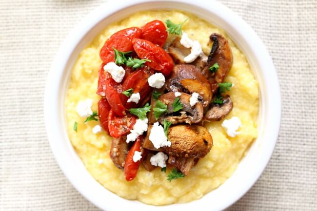 Slow Cooker Creamy Polenta with Roasted Tomatoes--easiest to make polenta ever, thanks to your slow cooker! Creamy polenta is served hot with balsamic drizzled roasted tomatoes, mushrooms and garlic and then topped with tart goat cheese. A perfect meatless meal that will leave you feeling satisfied. 