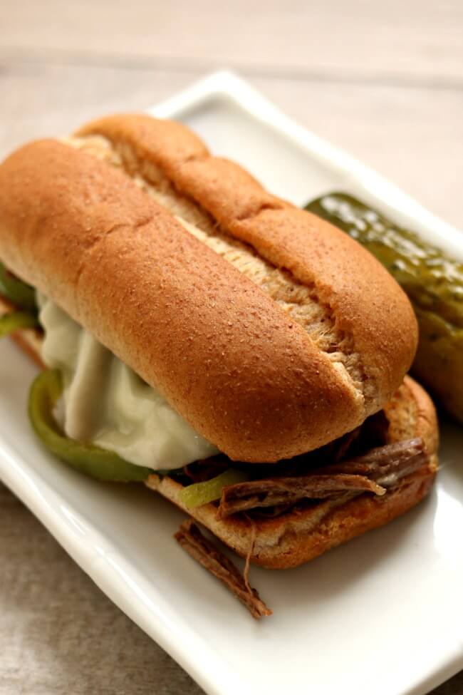 Instant Pot/Slow Cooker Philly Cheesesteak Sandwiches--tender shredded beef and green peppers are cooked in your electric pressure cooker or slow cooker. The beef is piled onto toasted buns that are slathered with mustard and mayo and then topped with melty cheese. 