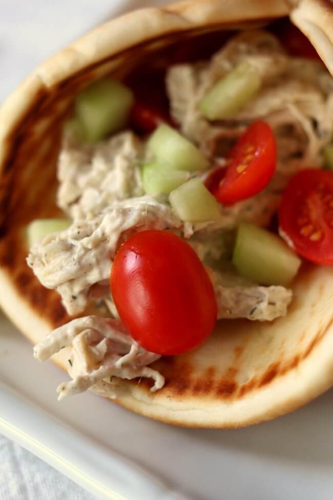 Slow Cooker Creamy Greek Chicken Pitas--a very easy recipe with just a handful of ingredients that tastes absolutely amazing! Cream cheese is stirred into shredded chicken with Greek seasonings and lemon juice and then served on pita bread and topped with tomatoes and cucumbers.  A simple family friendly meal that everyone will love.