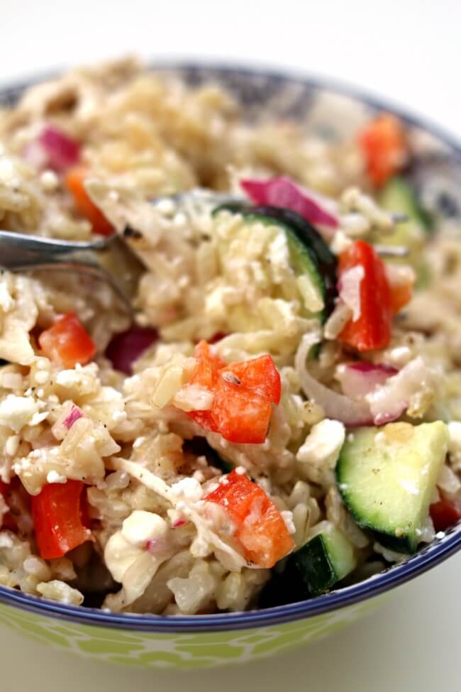 Instant Pot Greek Chicken Rice Bowls--brown rice and chicken are tossed with a lemon juice, olive oil, fresh garlic and vinegar dressing. Diced cucumber, red bell pepper, red onion and feta cheese are stirred into the rice to complete the one pot meal. 