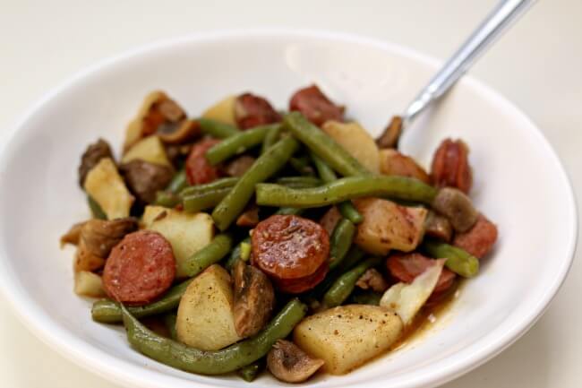 Slow Cooker Cajun Sausage, Potatoes and Green Beans--an easy one pot meal of cajun-style andouille sausage, quartered red potatoes, fresh green beans and sliced mushrooms. Drizzle the buttery broth over the potatoes for maximum flavor