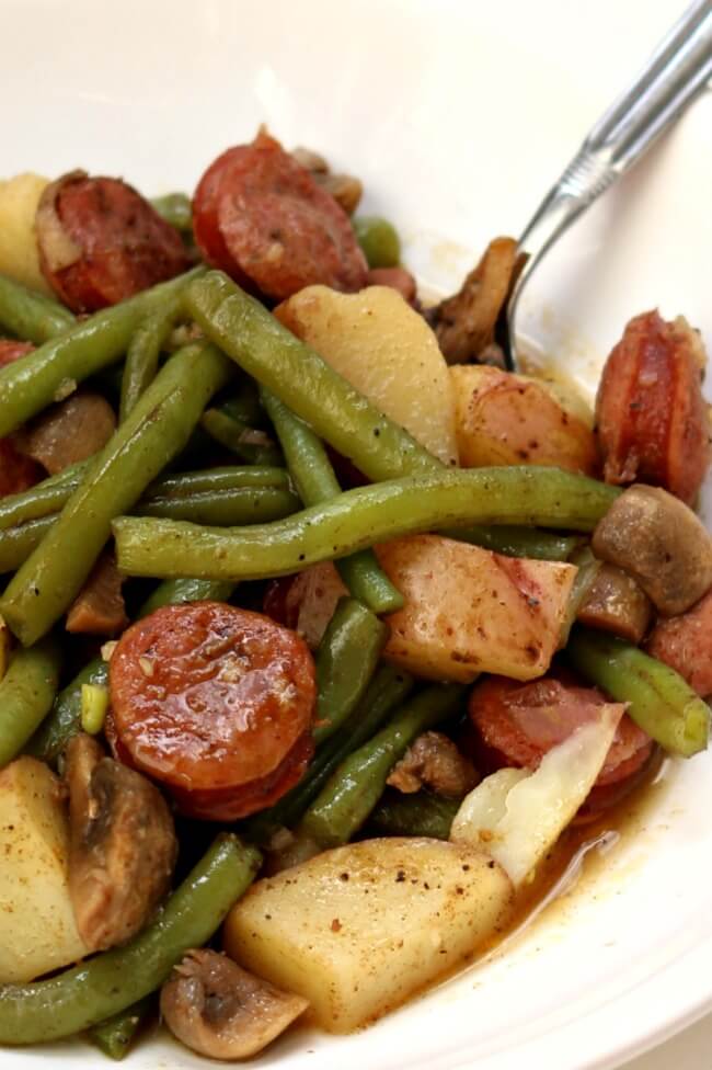 Slow Cooker Cajun Sausage, Potatoes and Green Beans--an easy one pot meal of cajun-style andouille sausage, quartered red potatoes, fresh green beans and sliced mushrooms. Drizzle the buttery broth over the potatoes for maximum flavor