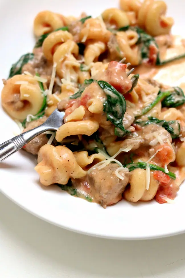 Instant Pot Creamy Sausage Parmesan Pasta--curly al dente pasta is enveloped in a creamy sauce with bites of baby spinach, petite tomatoes and Italian sausage.