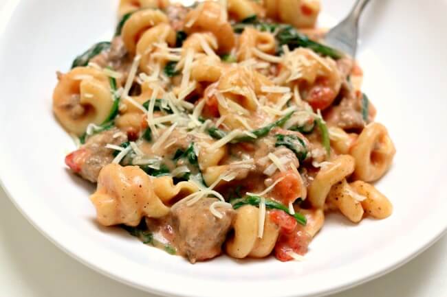 Instant Pot Creamy Sausage Parmesan Pasta--curly al dente pasta is enveloped in a creamy sauce with bites of baby spinach, petite tomatoes and Italian sausage.