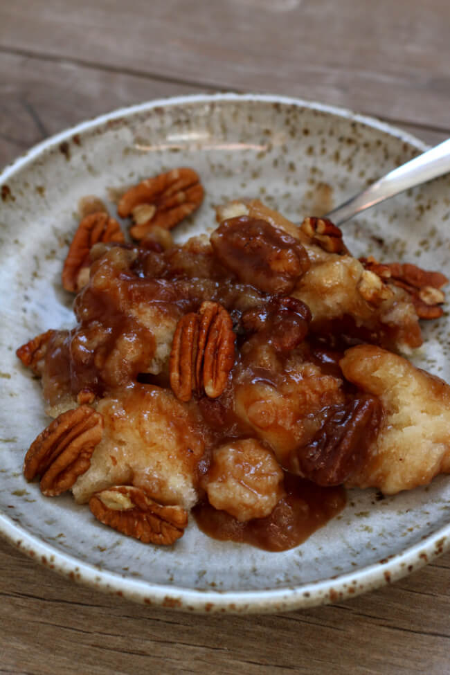Slow Cooker Praline Pecan Cobber--a gooey, caramelly praline pecan cobbler dessert that will blow your socks off. With a scoop of vanilla ice cream or whipped cream it tastes like heaven in your mouth. 