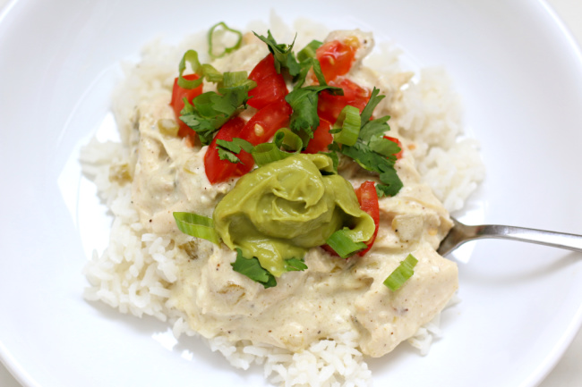 Slow Cooker White Chicken Enchilada Bowls--chopped chicken is encompassed in a velvety white sauce made with sour cream, cream cheese and diced green chilies. The sauce is served over rice and topped with colorful toppings. An easy way to enjoy the flavors of enchiladas without a ton of work. 