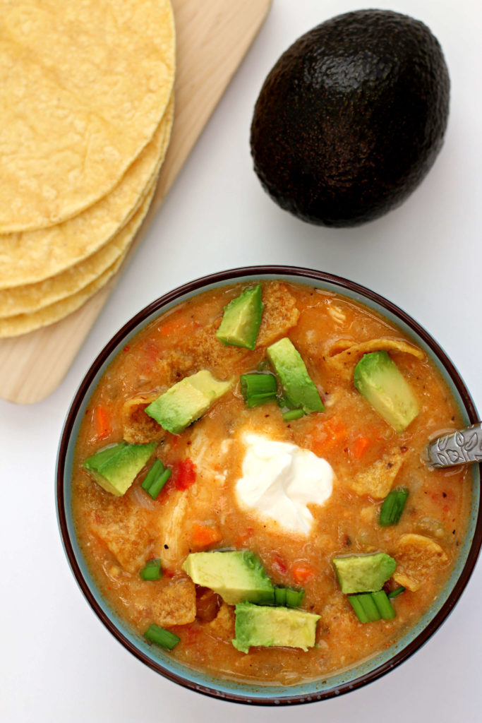 Slow Cooker Chicken Tortilla Soup--tortilla soup that is made with actual tortillas! The corn tortillas slow cook along with the bites of chicken, tomatoes, veggies and broth and then they thicken the soup into a lovely consistency. You're going to love this simple way to make real tortilla soup!