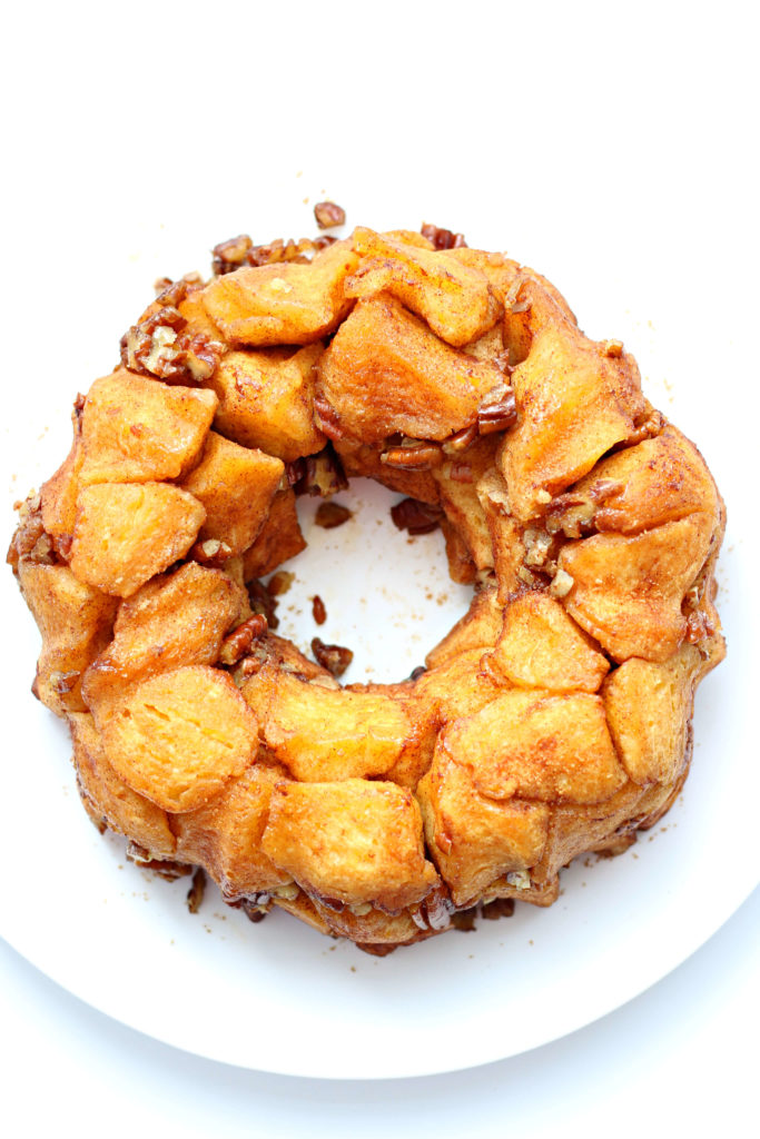 A white plate with a bundt cake shape of pull apart biscuit monkey bread on top