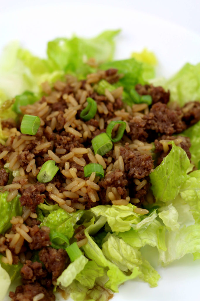 chopped romaine lettuce on a white plate with ground meat and rice on top