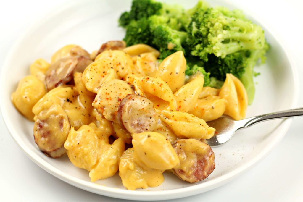 pasta and sausage on a white plate with broccoli florets