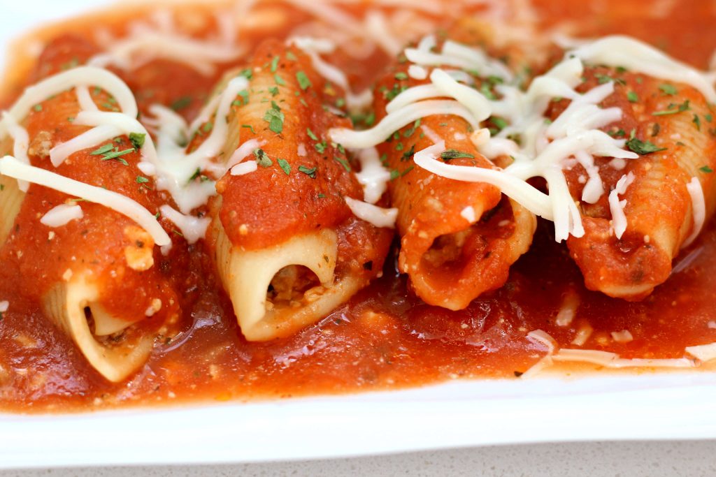stuffed pasta shells on a plate with red sauce and mozzarella cheese