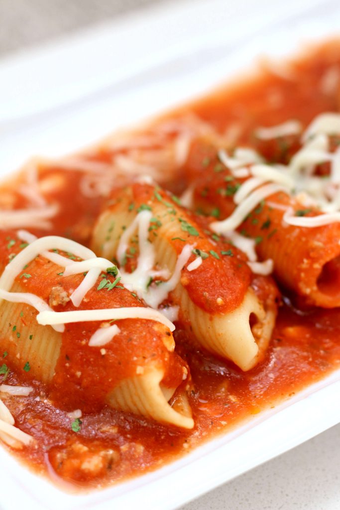 stuffed pasta shells on a plate with red sauce and mozzarella cheese