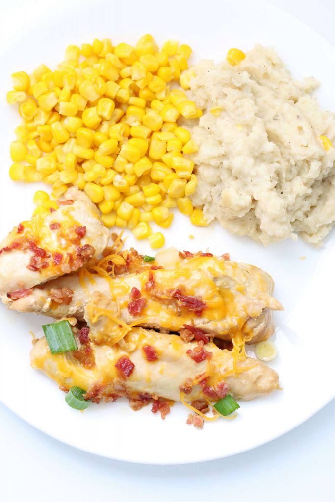 chicken with corn and mashed potatoes on a white place
