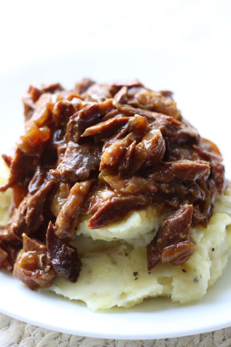 Slow Cooker Round Steak and Gravy--tender beef, onions, garlic and au jus gravy for a simple dump-and-go dinner that’s perfect served over mashed potatoes or egg noodles.