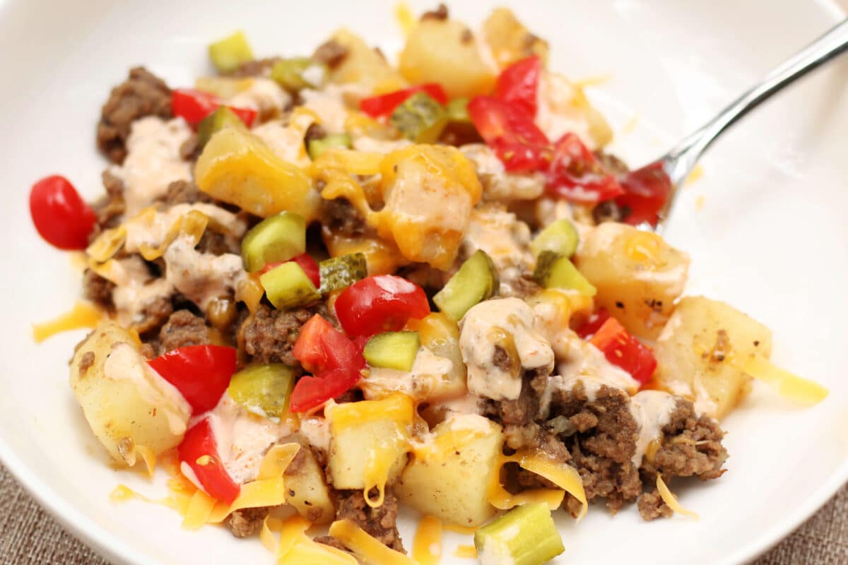 In-N-Out Animal Style Cheeseburger Casserole--an easy Instant Pot dinner with seasoned ground beef, tender potatoes, melted cheddar cheese, pickles, tomatoes and a creamy homemade burger sauce.