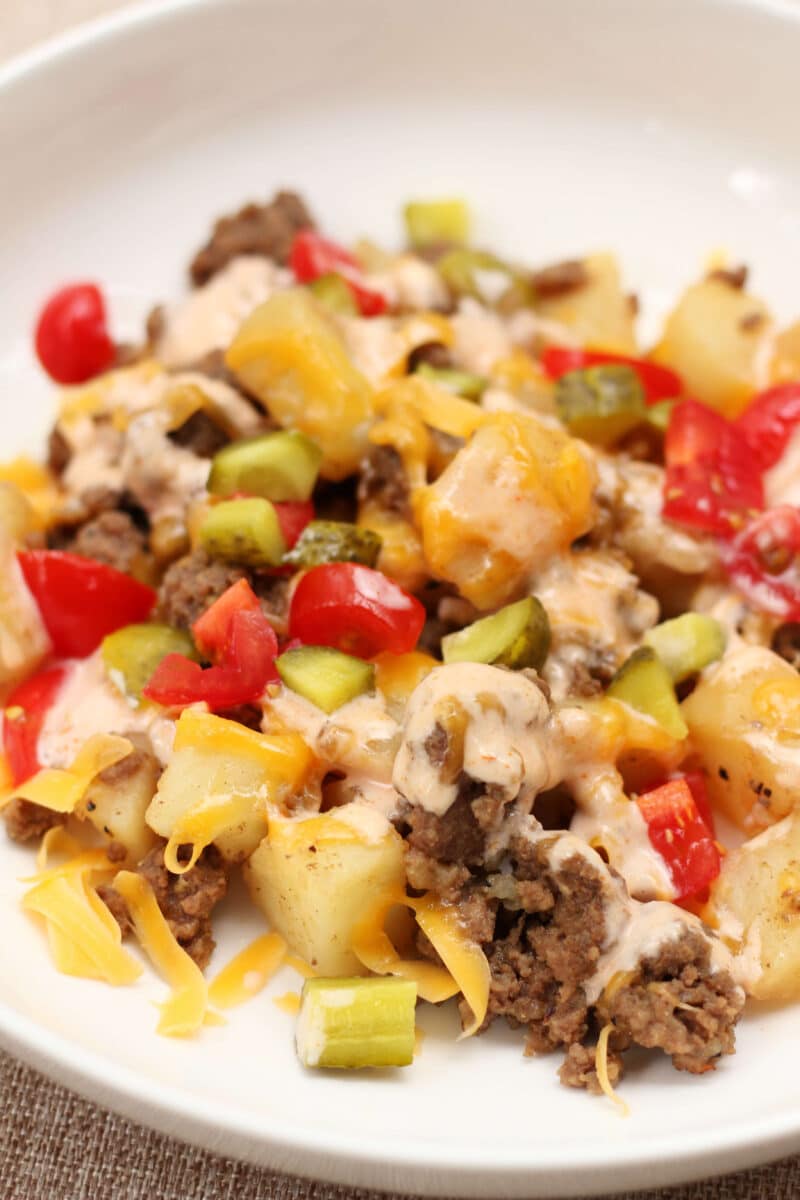 In-N-Out Animal Style Cheeseburger Casserole--an easy Instant Pot dinner with seasoned ground beef, tender potatoes, melted cheddar cheese, pickles, tomatoes and a creamy homemade burger sauce.