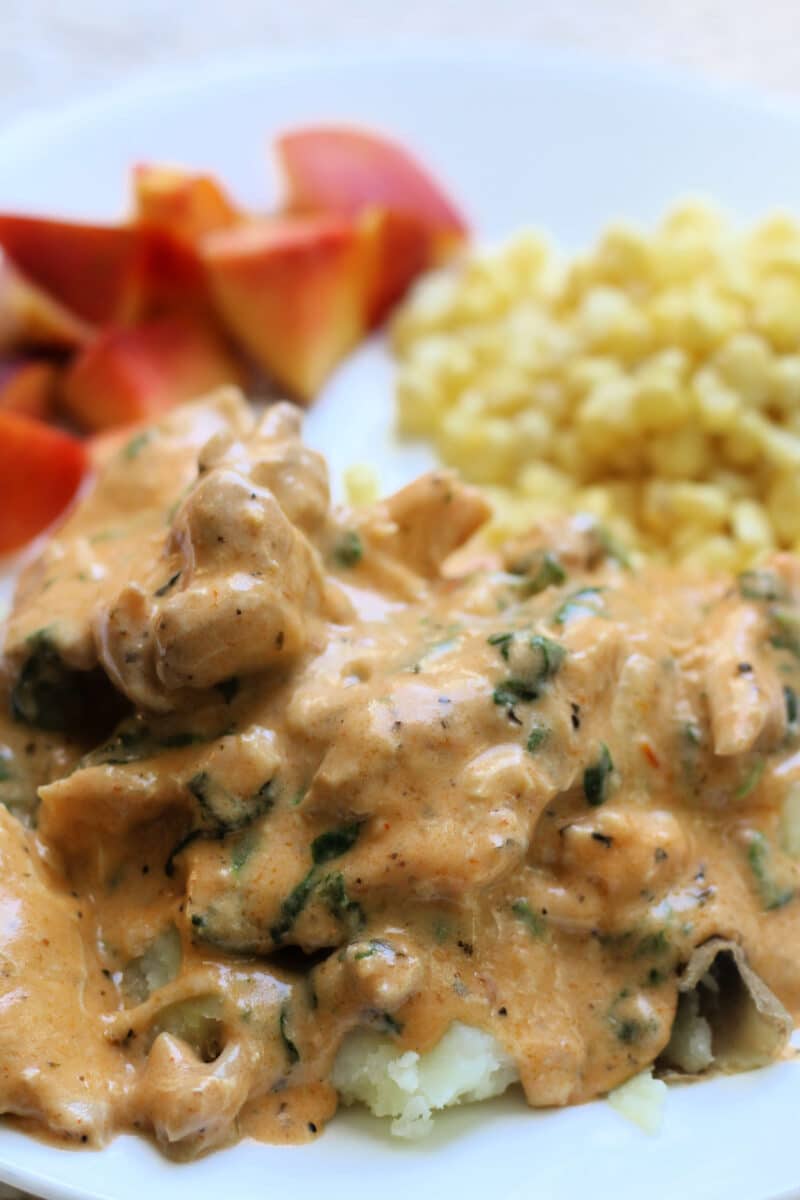 Tuscan Style Crockpot Chicken--an easy slow cooker or Instant Pot dinner made with tender chicken thighs, whole garlic cloves, Parmesan, spinach and a sun-dried tomato pesto cream sauce.