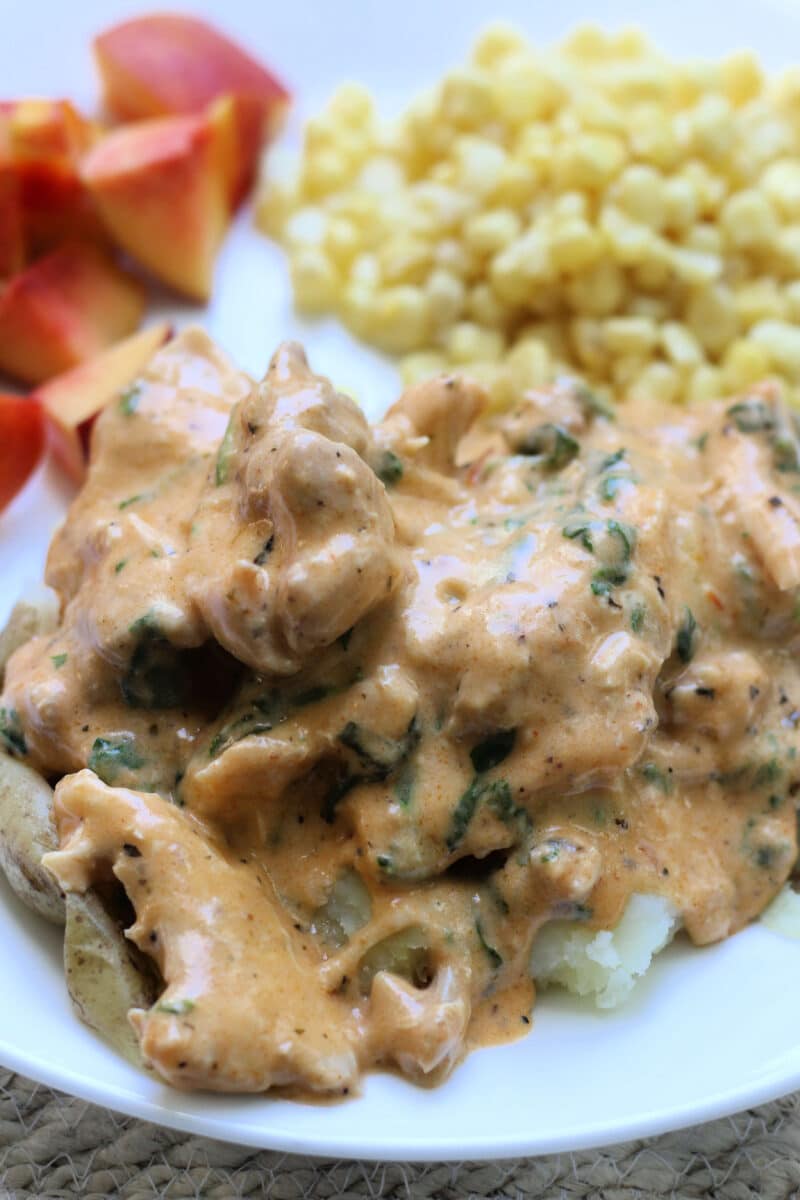Tuscan Style Crockpot Chicken--an easy slow cooker or Instant Pot dinner made with tender chicken thighs, whole garlic cloves, Parmesan, spinach and a sun-dried tomato pesto cream sauce.