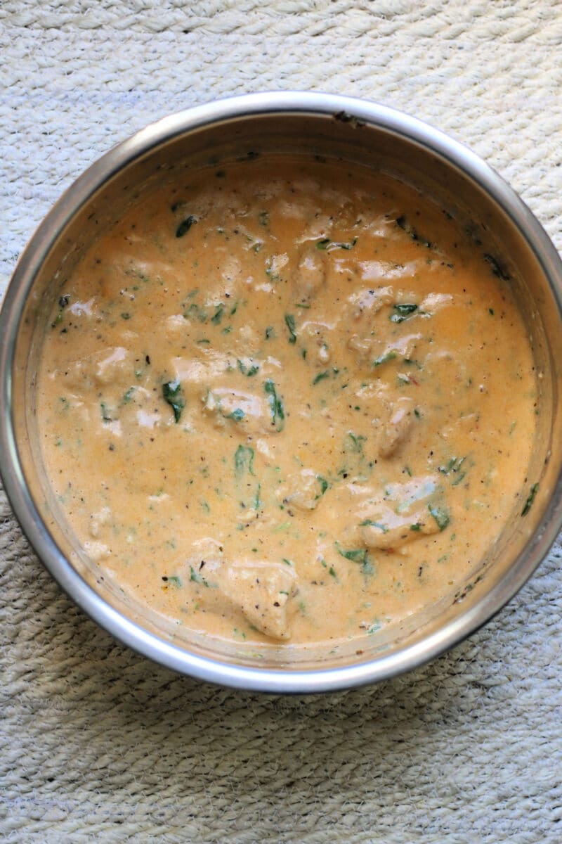 Tuscan Style Crockpot Chicken--an easy slow cooker or Instant Pot dinner made with tender chicken thighs, whole garlic cloves, Parmesan, spinach and a sun-dried tomato pesto cream sauce.