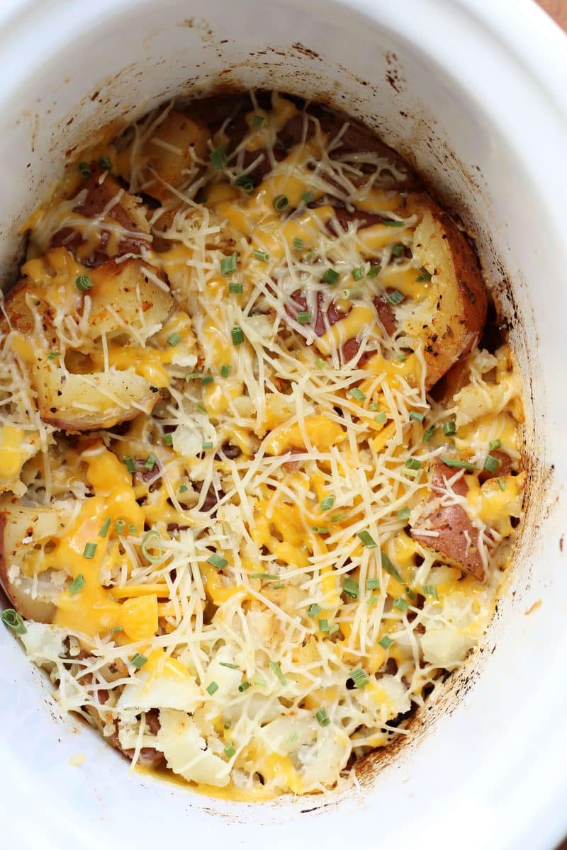 Slow Cooker Smashed Potato Bake--tender red potatoes coated in butter, garlic and seasonings, lightly smashed and finished with melted cheddar and Parmesan cheese.