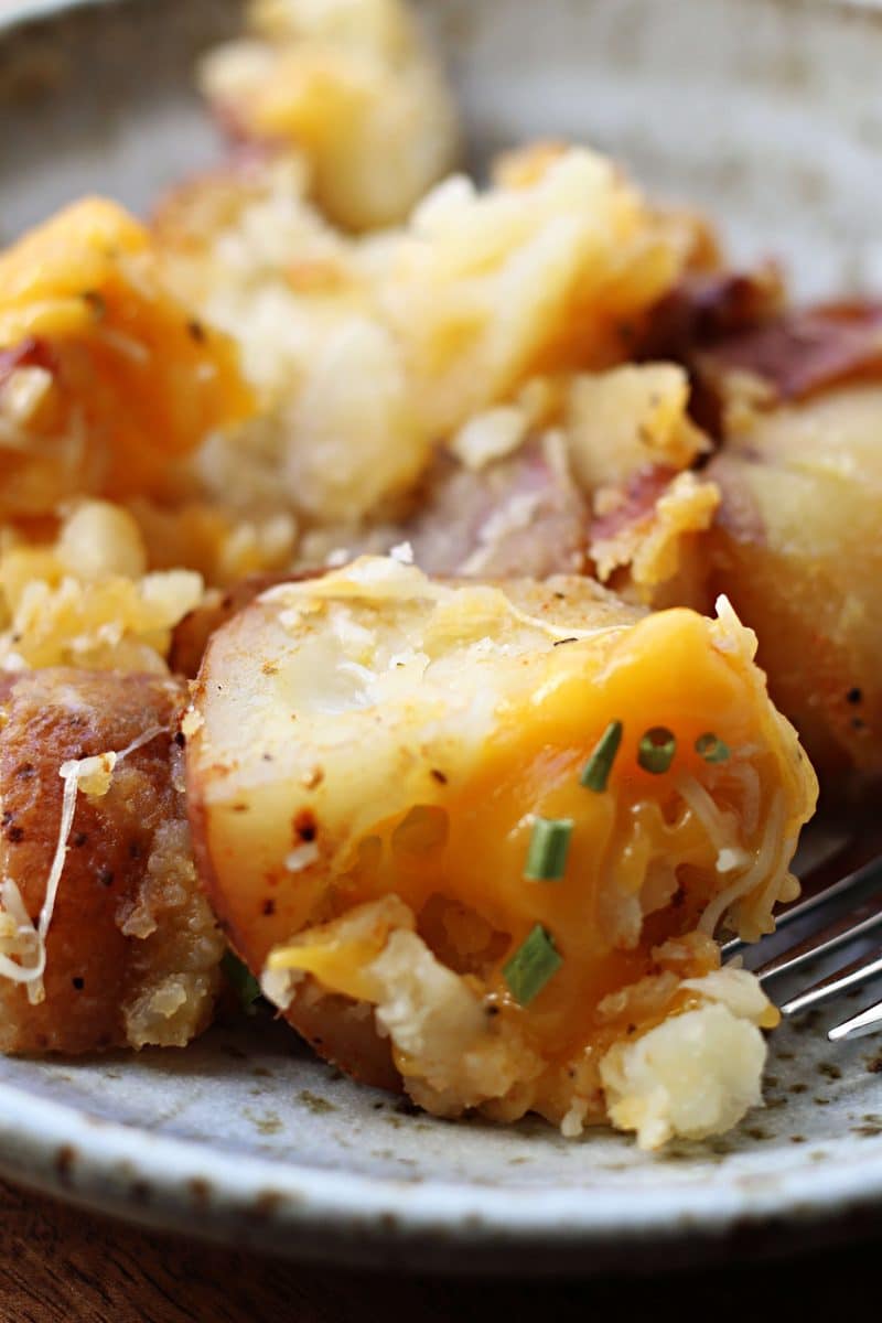 Slow Cooker Smashed Potato Bake--tender red potatoes coated in butter, garlic and seasonings, lightly smashed and finished with melted cheddar and Parmesan cheese.