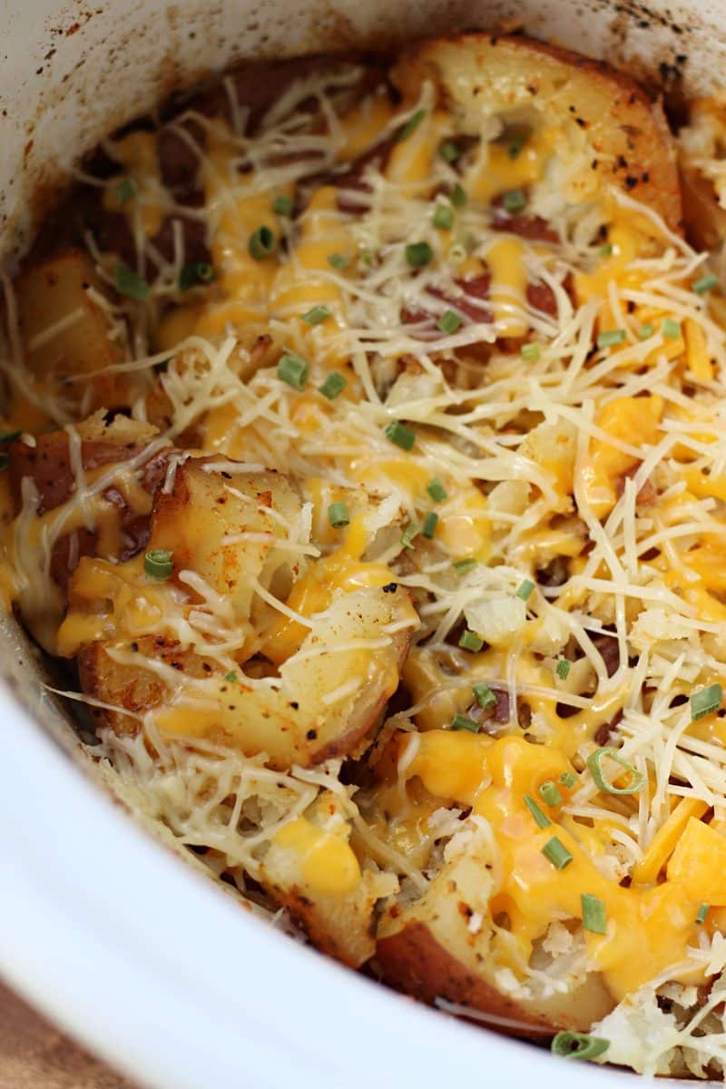 Slow Cooker Smashed Potato Bake--tender red potatoes coated in butter, garlic and seasonings, lightly smashed and finished with melted cheddar and Parmesan cheese.