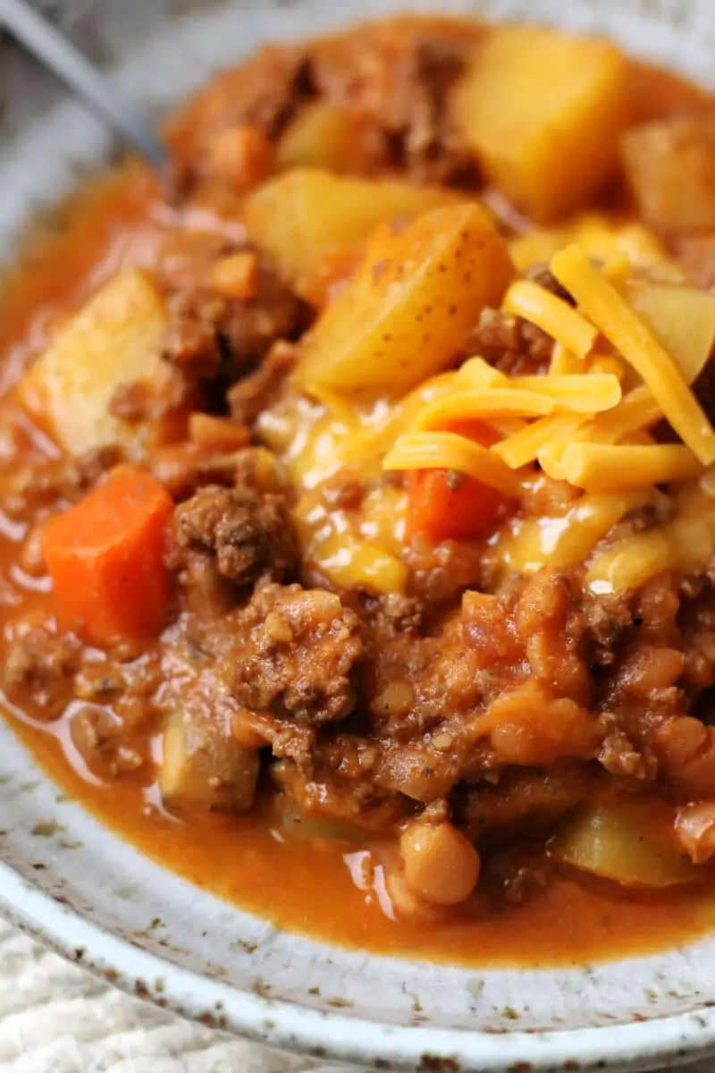 Slow Cooker Lumberjack Casserole--a crockpot meal made with ground beef, tender potatoes, carrots, mushrooms, pork and beans and melted cheddar cheese.