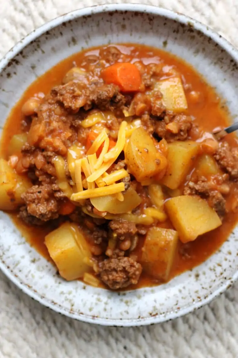 Slow Cooker Lumberjack Casserole--a crockpot meal made with ground beef, tender potatoes, carrots, mushrooms, pork and beans and melted cheddar cheese.