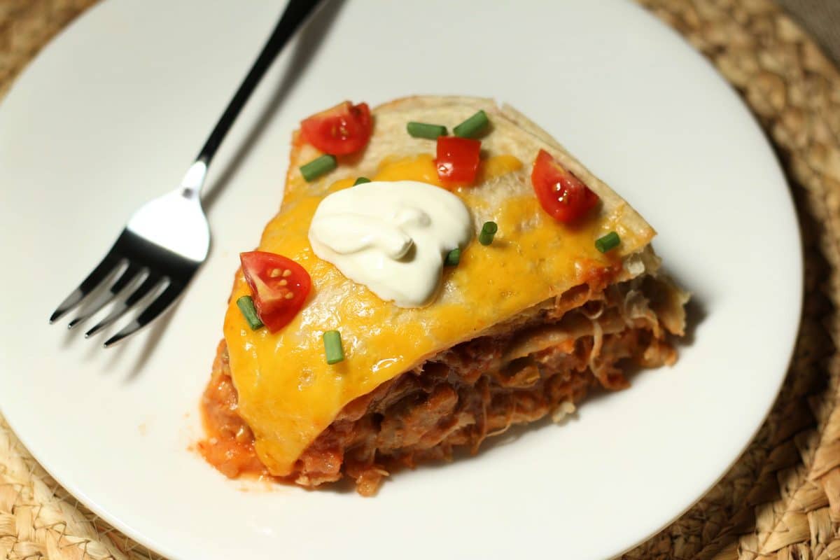 Mexican lasagna is made with layers of flour tortillas, shredded chicken, refried beans, salsa and melted cheddar cheese for a simple, cheesy dinner.